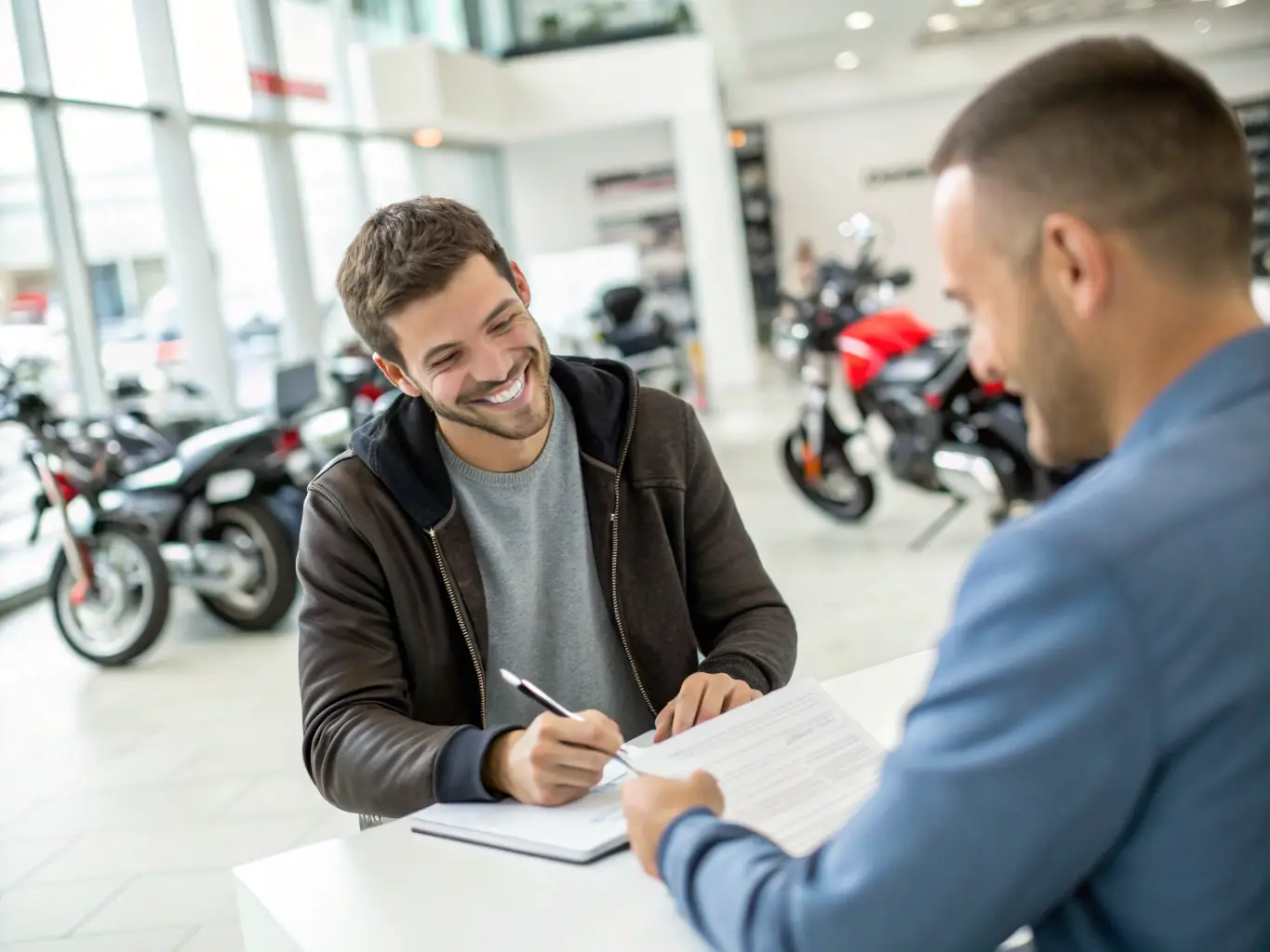 A customer is happily signing financing paperwork at ElectroDrive Imports, with a salesperson assisting and explaining the terms.